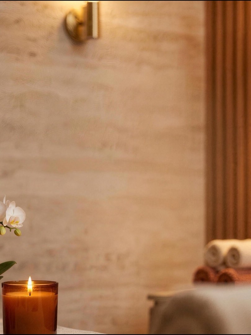 Warm salon-interieur met travertin, houten wand, kaars en zachte handdoeken